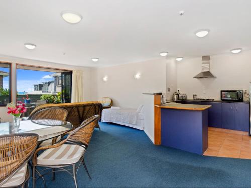 a kitchen and living room with a table and chairs at Boatshed Motel Apartments in Mount Maunganui