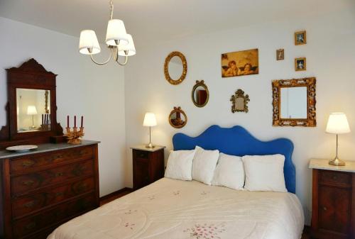 a bedroom with a bed with a blue headboard and mirrors at Casa Dante in Vivo dʼOrcia