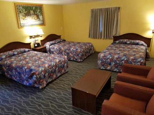 Una habitación de hotel con dos camas y una mesa y sillas. en Budget Host Inn, en Bedford