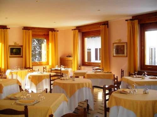 a room with tables and chairs with yellow curtains at Centrale in Courmayeur