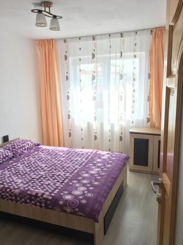 - une chambre avec un lit violet et une fenêtre dans l'établissement 3 rooms ApartHotel, à Braşov