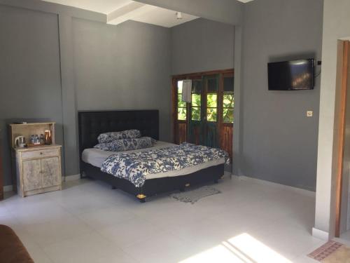 a bedroom with a bed and a tv on the wall at Kayu Tua Villa in Uluwatu