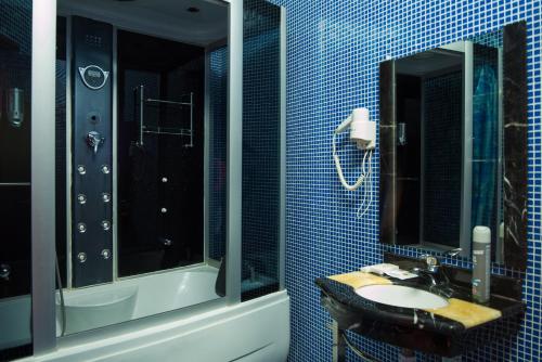 ein blau gefliestes Bad mit einem Waschbecken und einem Spiegel in der Unterkunft Rubin Hotel Complex in Jakutsk