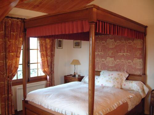 a bedroom with a canopy bed and a window at La Minauderie in Écully