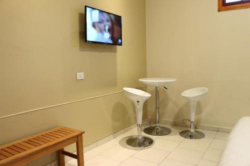 a room with two stools and a tv on the wall at Eclat Suites Hotel Boutique in Villa Mercedes