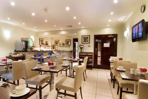 a restaurant with tables and chairs and a kitchen at The Premier Notting Hill in London
