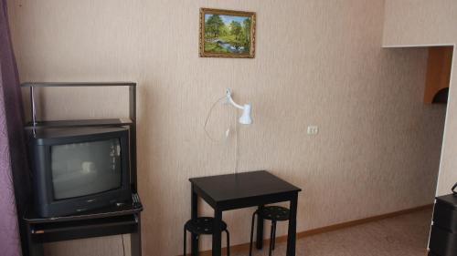 トムスクにあるApartments on Frunze 126のテーブル、テレビ、テーブル、スツールが備わるお部屋