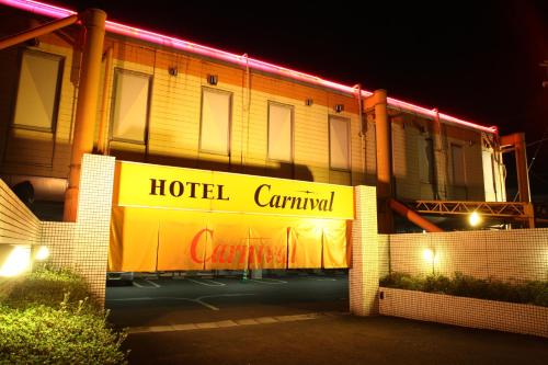 un cartel de carnaval del hotel frente a un edificio por la noche en Hotel Carnival (Love Hotel), en Miyaki