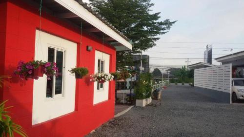 a red and white building with flower boxes on it at Love Box Resort in Samut Prakan