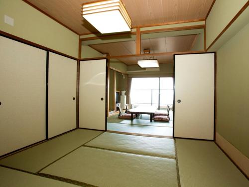 Itoen Hotel Atagawa في هيغاشيزو: غرفه فاضيه فيها ابواب وغرفه فيها طاوله