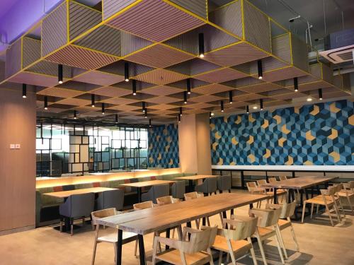 a dining room with tables and chairs and a wall at YELLO Hotel Paskal Bandung in Bandung