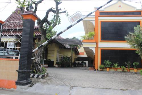 a street sign is tied to a pole in front of a building at Simpang Tujuh in Cepu