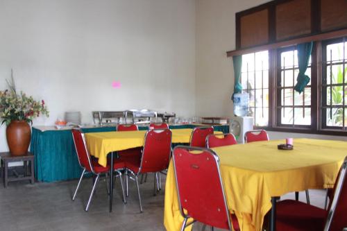a room with yellow tables and red chairs at Simpang Tujuh in Cepu
