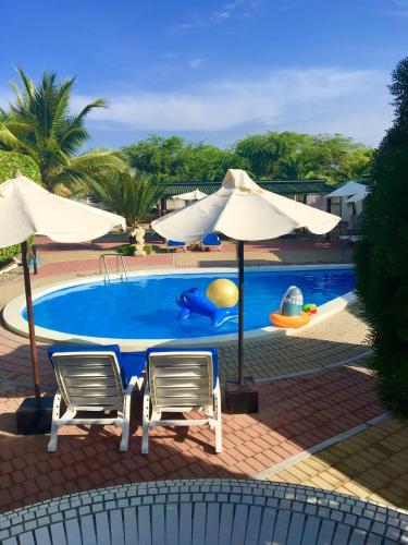 a swimming pool with two chairs and an umbrella at Hotel Casa Playa Zorritos in Zorritos