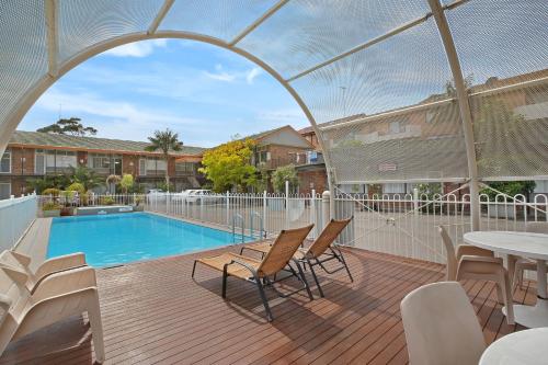 a patio with a pool and chairs and a table at Ultimate Apartments Bondi Beach in Sydney