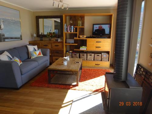 a living room with a blue couch and a table at Beach Buoy Opossum Bay in South Arm