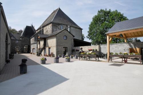 a large stone building with benches and a pavilion at Château Ferme de Laval in Sainte-Ode