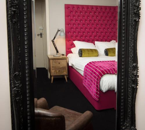 a bedroom with a bed and a mirror at The Bull Inn in Mildenhall