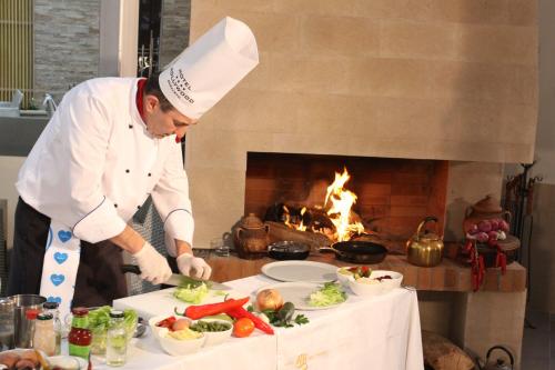 a chef preparing food in front of a fireplace at Hollywood Hotel in Sarajevo
