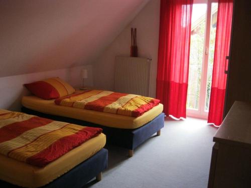 two beds in a room with red curtains at Haus am Redder in Flintbek