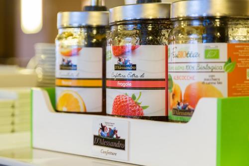 three jars of jam on a shelf with fruit at Villa Maria Hotel & SPA in Francavilla al Mare
