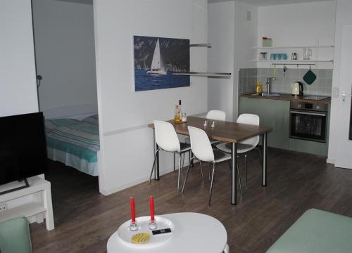 a room with a table and chairs and a kitchen at Ferienwohnung Homeyer in Schilksee