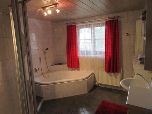 ein Badezimmer mit einer Badewanne und einem roten Duschvorhang in der Unterkunft Ferienhäusl Hubert und Staller in Kaltenbach