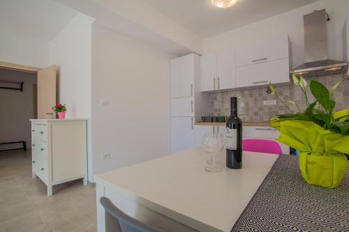 a white kitchen with a bottle of wine on a counter at Apartment Garden breeze in Cres