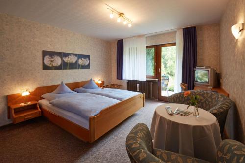 Habitación de hotel con cama, mesa y sillas en Haus am Kaltenbach en Enzklösterle