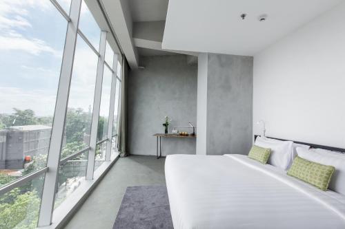 a bedroom with a large white bed and large windows at Janevalla Bandung in Bandung