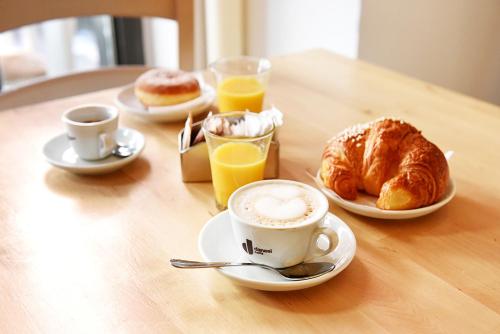 a table with a cup of coffee and croissants and orange juice at Grammy Suite in Rome