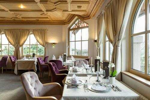 a dining room with tables and chairs and windows at Hotel Burggräflerhof in Merano