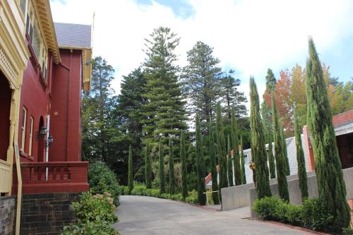 a driveway next to a red house with trees at Pirralilla Estate Adelaide Hills in Aldgate