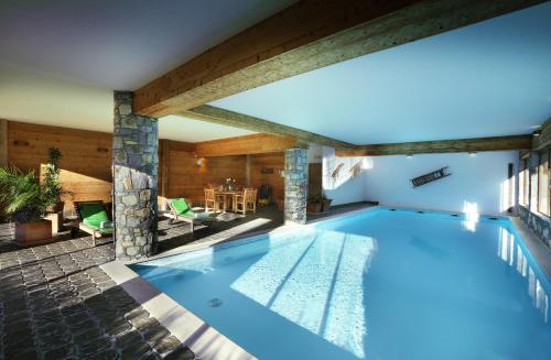 an indoor swimming pool with blue water in a house at Hotel Autantic in Bourg-Saint-Maurice