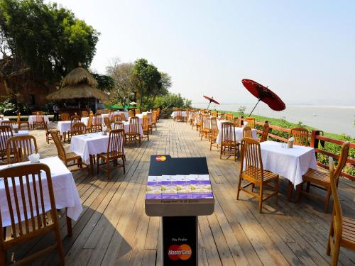 a row of tables and chairs on a deck at KMA Bagan Hotel River View in Bagan