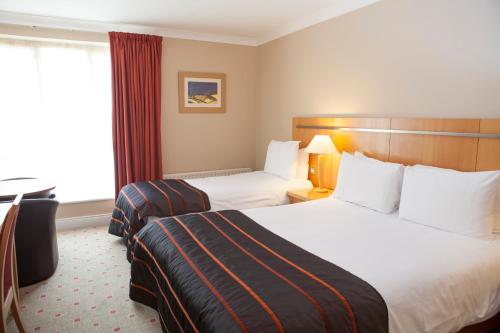 a hotel room with two beds and a window at Lahinch Coast Hotel and Suites in Lahinch