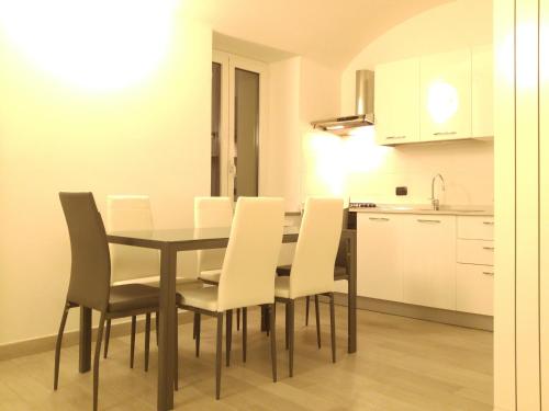 a dining room table with white chairs and a kitchen at Il Cuore del Borgo - Holiday Home in Borgomaro