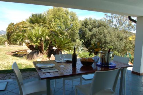 a wooden table with white chairs and a bottle of wine at Villa delle torri in Pula
