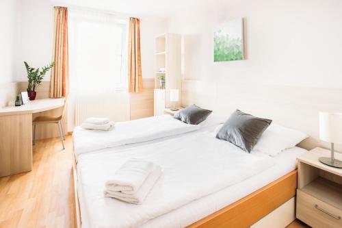 um quarto com 2 camas com lençóis brancos e uma secretária em myNext - Hotel Rudy em Viena