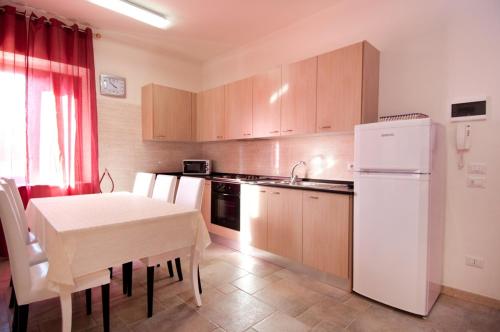 a kitchen with a table and a white refrigerator at Rifugio Delle Grotte in Castellana Grotte