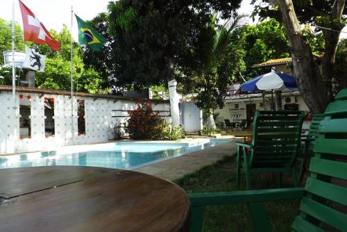 a pool with a wooden table and two flags at Pousada Chalé Suiço in Parnaíba