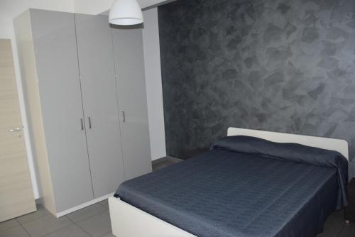 a bedroom with a bed and a gray wall at Riposto Etna Taormina Mare in Riposto