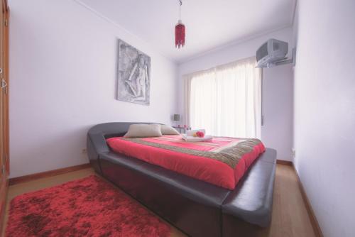 a large bed in a room with a red blanket at Welcome Barra Apartment in Gafanha da Nazaré