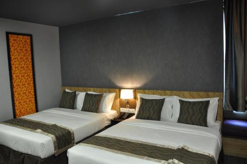 a hotel room with two beds and a lamp at Valya Hotel, Kuala Terengganu in Kuala Terengganu