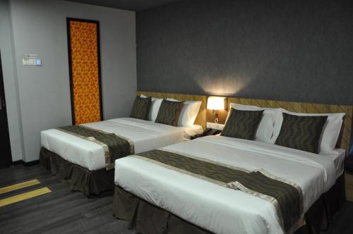 a hotel room with two beds and a lamp at Valya Hotel, Kuala Terengganu in Kuala Terengganu