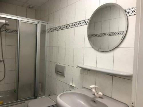 uma casa de banho com um chuveiro, um lavatório e um espelho. em Am Bahnhof em Wittenberg