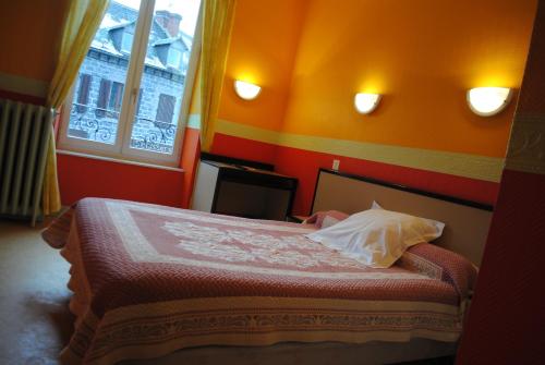 a bedroom with a bed with orange walls and a window at Hotel des voyageurs Chez Betty in Neussargues-Moissac