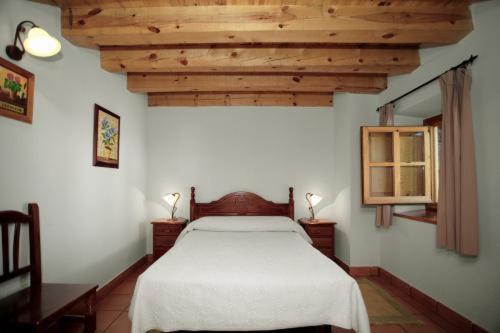a bedroom with a white bed and wooden ceilings at Casa Rural Soportales de Peguerinos in Peguerinos