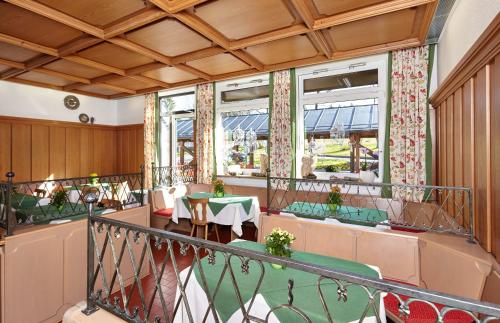 a restaurant with a balcony with tables and chairs at AURA-HOTEL Saulgrub in Saulgrub