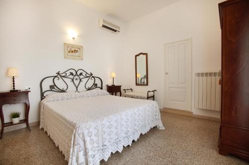 Schlafzimmer mit einem weißen Bett und einem Spiegel in der Unterkunft Agriturismo Masciarella in Carovigno